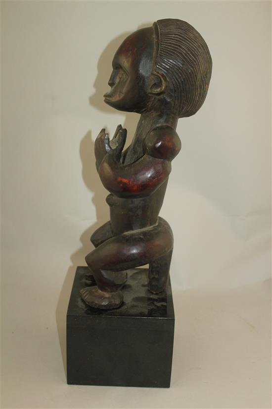 A West African carved hardwood figure of a seated male, overall 22in.